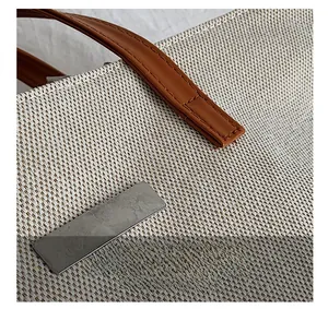 Close-up of a large canvas tote bag featuring textured weave and brown leather handle