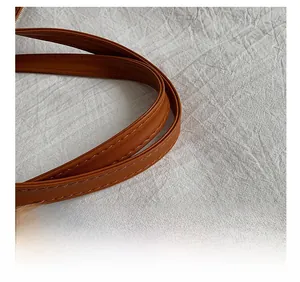 Close-up of brown leather handle with double stitching and smooth edge finish on tote bag