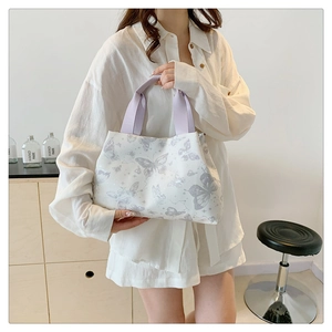 Détail du sac seau blanc avec imprimé papillon violet et poignées en tissu