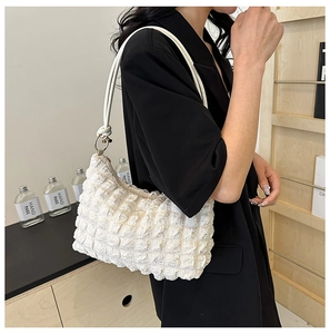 Detail view of cream-colored bubble texture bag with a sleek white leather shoulder strap