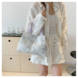Détail du sac cabas blanc avec imprimés papillons violets et anses tissées