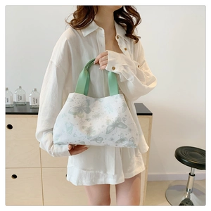 Détails d'un sac cabas blanc en toile avec motifs papillons et anses en ruban vert clair