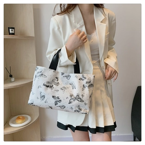 Détail d'un sac cabas blanc avec motifs papillons noirs élégants sur fond d'intérieur épuré