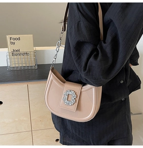 Side view of beige hobo bag with rhinestone buckle and chain strap on a model