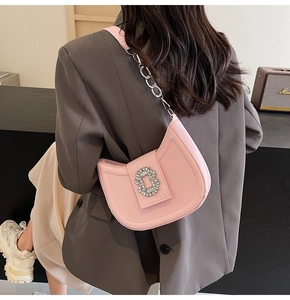 Detail of pink crescent shoulder bag with rhinestone buckle and silver chain on model