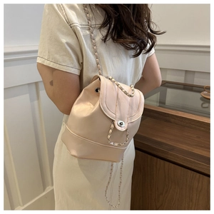 Detail of cream leather backpack featuring silver chain straps and a twist-lock closure