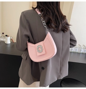 Detail of pink crescent bag with sparkling rectangular rhinestone buckle and metal chain strap