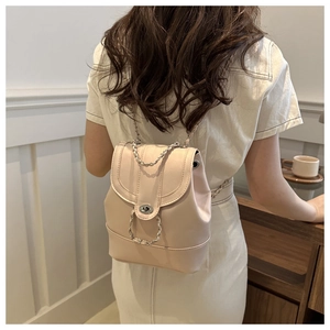 Detail of light pink faux leather backpack featuring metal twist lock and chain straps