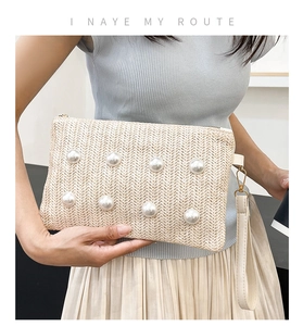 Detail of woven straw clutch with pearl embellishments and a gold-tone zipper