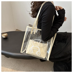 Macro detail of clear PVC tote bag with bear print and inner beige pouch shown on model