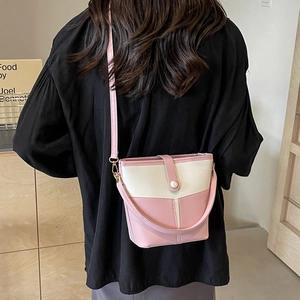 Borsa a secchiello bicolore rosa e crema con tracolla indossata da una modella