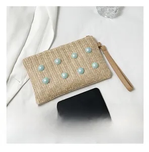 Detailed top view of a woven straw bag with blue pearls and brown leather strap