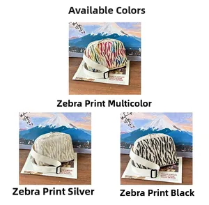 Détail de motif zébré pailleté sur sacs bandoulière tissés en forme de coquillage