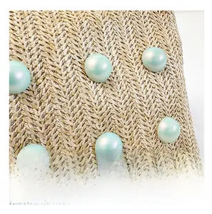 Detailed close-up of beige woven texture featuring light green pearlescent beads decoration