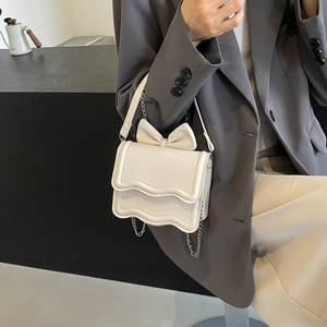 Creamy white crossbody bag with 3D bow and wave edges on a silver chain strap