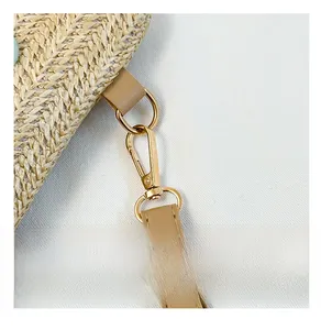 Close-up of golden metal buckle and brown leather strap on woven straw crossbody bag