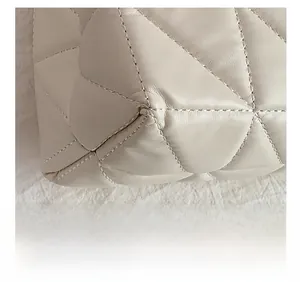 Macro shot of precise diamond quilting and stitching details on a cream leather tote bag