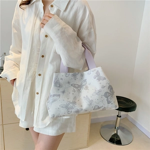 Sac fourre-tout blanc chic avec motif papillon et anses lilas porté par un mannequin