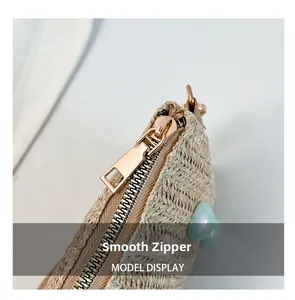 Detail of smooth metal zipper and woven texture on a minimalist straw square bag