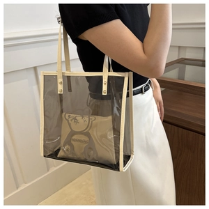 Close-up of clear PVC tote with cream leather trim and a cartoon bear canvas inner bag