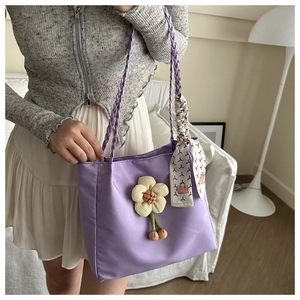 Detail of purple nylon tote bag featuring floral pendant and patterned scarf wrap handle