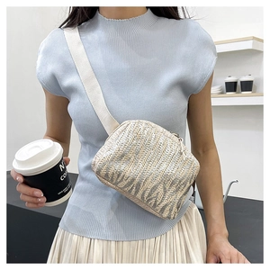 Détail d'un sac bandoulière en paille tissée à rayures avec large sangle blanche