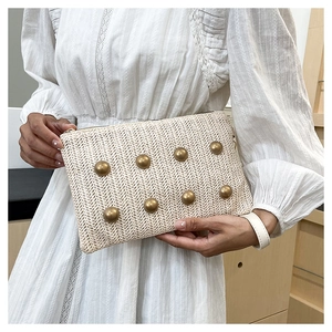 Detail of cream woven clutch with gold studs and textured zigzag pattern for summer