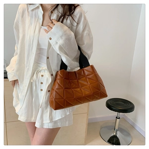 Close-up of brown quilted tote bag with geometric pattern and black fabric strap