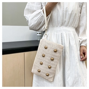 Detail of cream woven handbag featuring golden rivet studs and a matching wrist strap