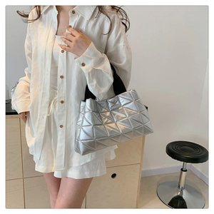 Silver quilted tote bag with geometric patterns and black straps shown in lifestyle setting
