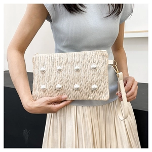 Detail of woven straw clutch with pearl accents and detachable wrist strap on model