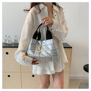 Detail of silver tote bag with quilted geometric pattern and black fabric handles