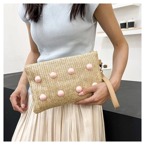Detail shot of hand-woven straw crossbody bag with pink bead charms and leather handle