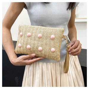 Detail of woven straw handbag featuring pink beads and a khaki leather wrist strap