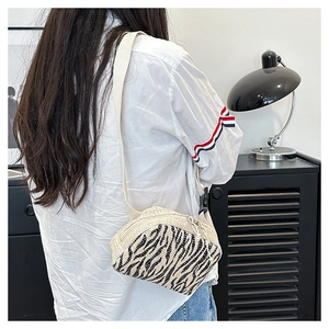 Sac bandoulière en paille avec patch zèbre porté par un modèle dans un cadre décontracté
