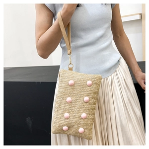Detail of hand-woven straw crossbody bag featuring pink pearl accents and leather strap