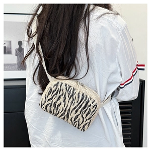 Détail macro du sac ceinture en paille tressée à motif zébré avec bandoulière réglable