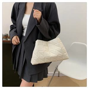 Close-up of creamy white tote bag featuring 3D triangle pattern and black handles
