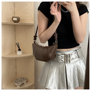 Détails d'un sac croissant en cuir marron montrant la texture plissée et la bandoulière nouée