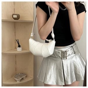 Close-up of white croissant shoulder bag with pleated leather texture and knot detail