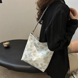 Elegant white shoulder bag with gold and blue butterfly embroidery shown on a model