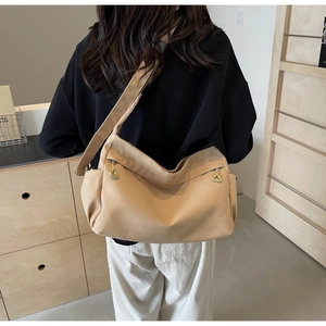 Rear view of a model wearing a beige minimalist large capacity tote bag with green zipper details