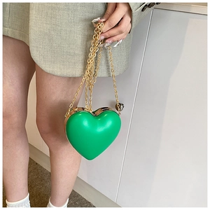 Dettaglio borsa a cuore verde brillante rigida con finiture dorate e tracolla a catena