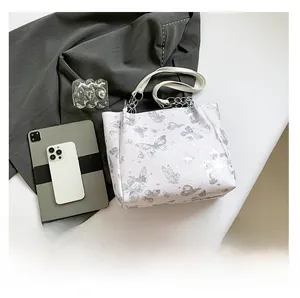 Detail van de witte tote tas met vlinderprint en stijlvolle zilveren metalen kettinggreep