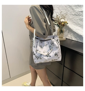 Detail van de tote bag met vlinderprint en zilveren ketting gedragen door model