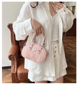 Pink bowling bag with white butterfly charm shown on model in a retro home setting