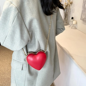 Elegante borsa a tracolla a forma di cuore rosso con catena dorata su blazer grigio