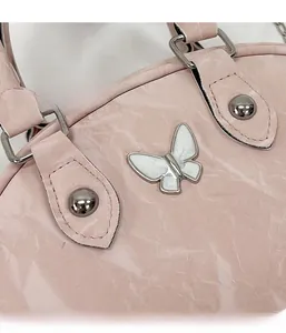 Detail of pink marble-patterned leather bag with silver butterfly charm and metal rivets