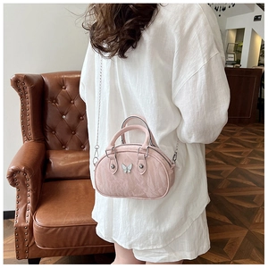 Detail of light pink pleated bowling bag with silver butterfly metal ornament