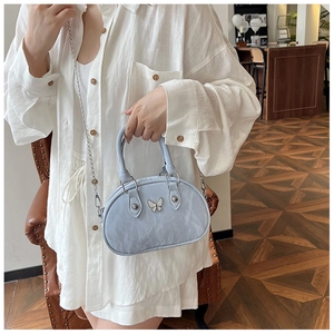 Detail of light blue bow handbag with silver butterfly buckle and chain strap